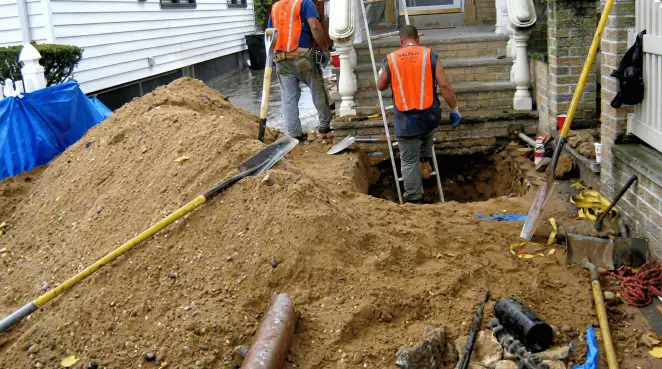 Contractors performing foundation protection and exterior drainage excavation near residential home steps in Ann Arbor, MI